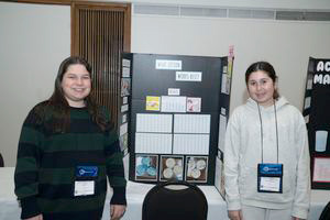 Two students standing beside their exhibits at the STEM fair